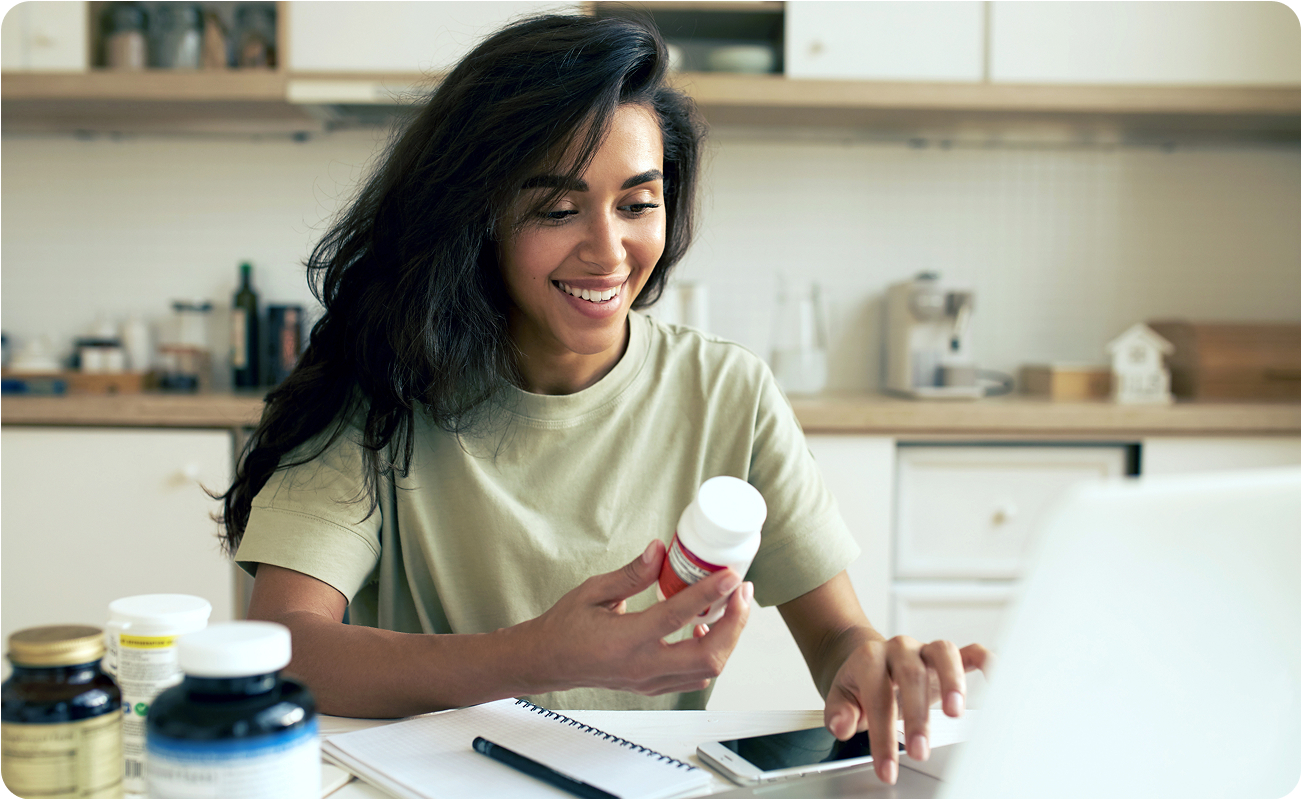 A customer looking at their pill bottle and phone, placing an order for their refill.
